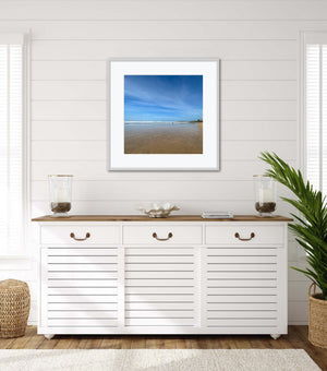 White cabinet with wooden top in a room with a framed beach scene on the wall.
