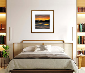 Bedroom with a bed, bookshelves, and framed orange sunrise artwork on the wall.