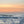 Sunset over the ocean with waves crashing on the shore