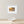 Framed artwork of a sunset over water on a wall above a wooden surface with a decorative shell.