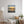 Living room with a painting of three people on a beach at sunset, reflected in wet sand. The room also has a lamp, and a sofa.