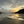 Beach scene with sunset reflected in wet sand and silhouetted headland