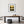 Dining room with a wooden table, chairs, and a framed landscape print of a marsh at sunrise on the wall.