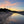 Beach scene with boats at sunrise, reflecting on water