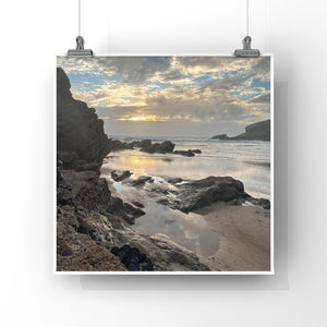 Beach scene with rocks and water, framed by a white border