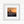 Photo of coastal flowers silhouetted against a sunset sky. Square print in white frame