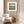 White armchair in a room with wooden walls and a framed picture of a sunset and people silhouetted over water.