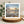 Greetings card withbeach photograph of clouds reflected in wet sand at sunset. On a wooden stand with decorative elements.
