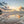 Beach scene with sunset and clouds reflecting on the water