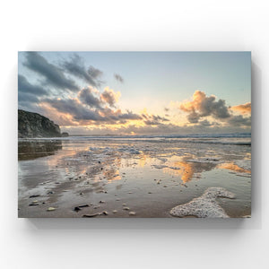 Beach scene with sunset , clouds, and water reflections.