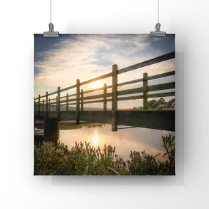 Wooden fence reflected in water with sunset sky hanging from two wires