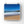 Beach scene with blue sky, ocean waves, and sandy shore.